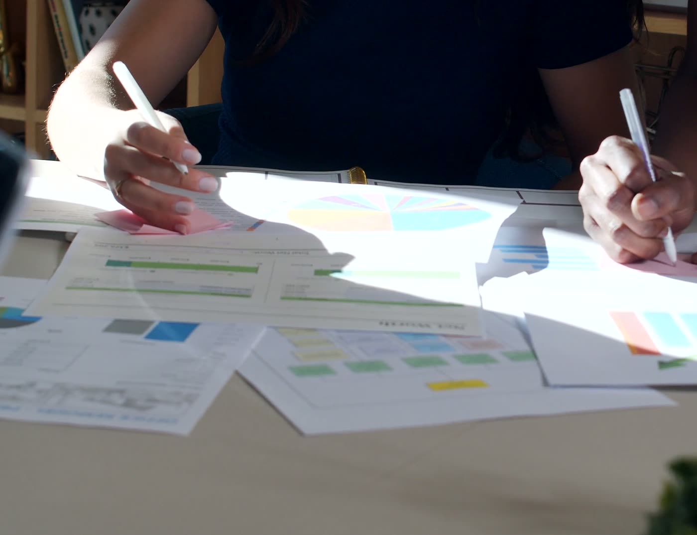 Handen bij een rapport met grafieken op tafel
